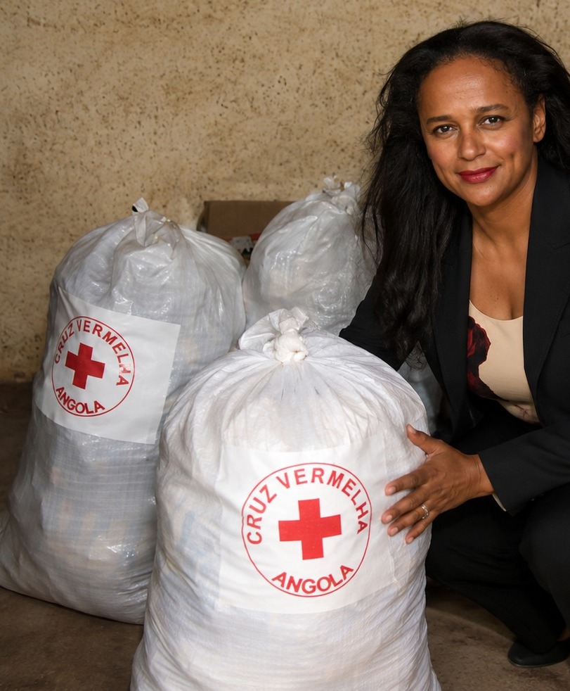 Imagem ilustrativa mostrando Isabel dos Santos junto a sacos de ajuda humanitária da Cruz Vermelha de Angola durante actividade institucional.