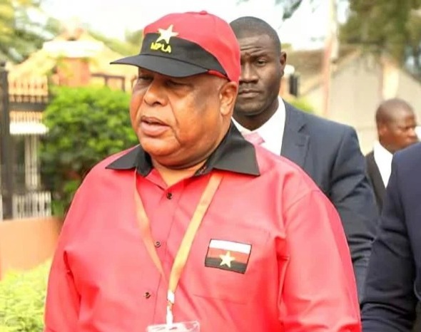 Higino Carneiro durante atividade política do MPLA em ambiente público, usando camisa vermelha e boné partidário.