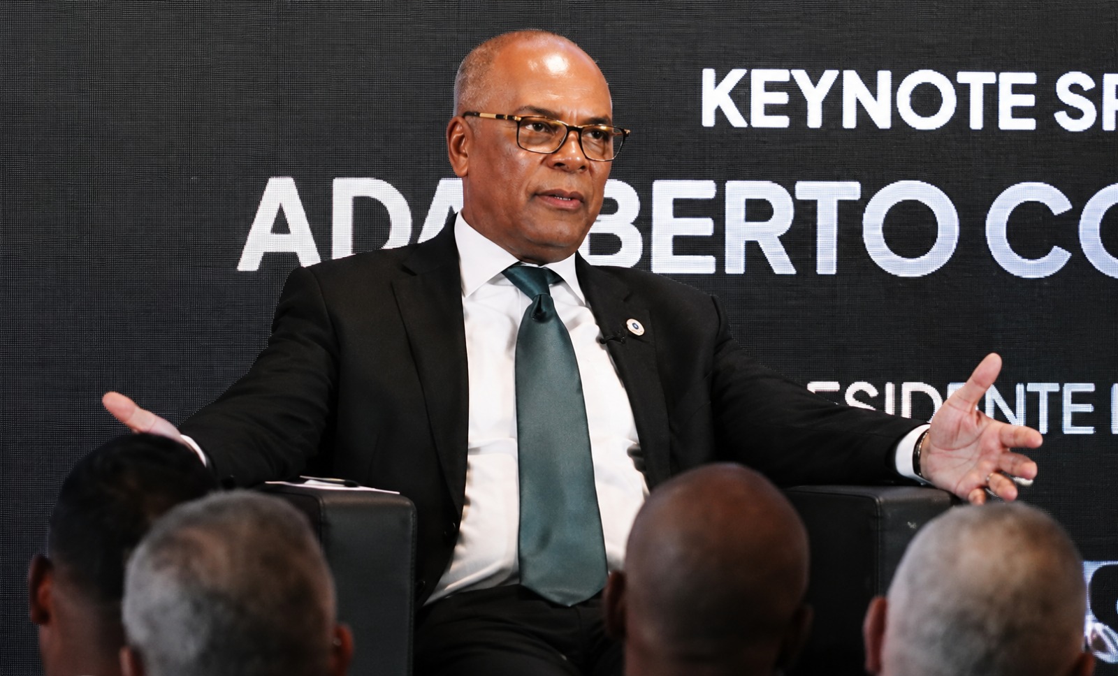 Adalberto Costa Júnior participa como orador numa conferência pública, discursando diante de uma audiência sobre reformas políticas e governação em Angola.